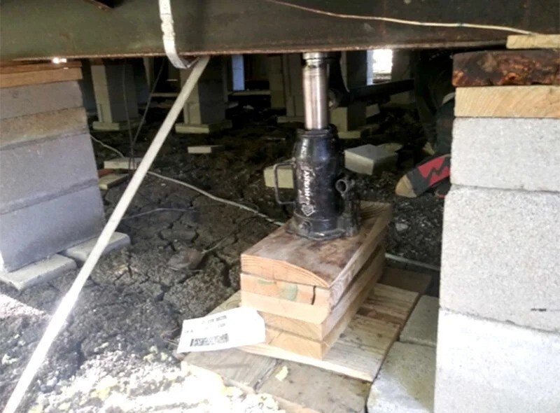 A jackhammer rests on a wooden platform, used for mobile home foundation repair.